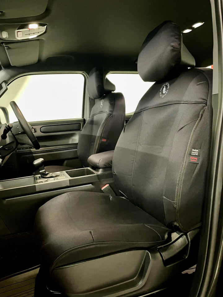Kia tasman interior showingblack denim seat covers on front seats.